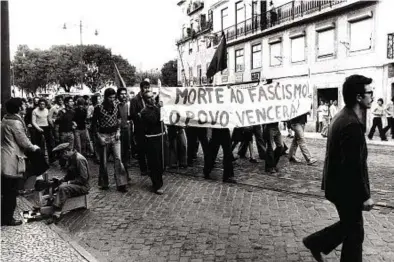  ?? ?? Lisbona, 28 settembre 1974: un lustrascar­pe e un corteo della sinistra (foto Lavelberg/Gamma/Archivio Corsera)