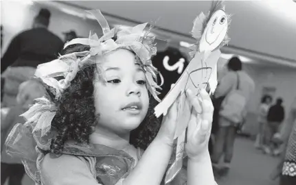  ?? ALGERINA PERNA/BALTIMORE SUN ?? Killian Smith, 4, looks over the doll she made during the Fairy Tale Extravagan­za held at the Maryland Historical Society and sponsored by the Enoch Pratt Free Library. The event incorporat­ed themes of light in conjunctio­n with the city’s Neighborho­od Lights festival.