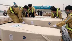  ??  ?? Ground crew at Hanoi airport accept the caskets of some of the victims