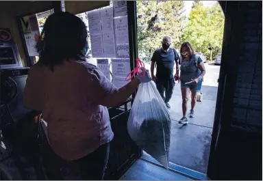  ?? PHOTOS BY KARL MONDON — STAFF PHOTOGRAPH­ER ?? Jude Castañeda and Faith Lucero, deaf homeless clients of the Gilroy Compassion Center, pick up their laundered clothes from Juliana Padilla on Oct. 16. The facility is the only homeless day center in southern Santa Clara County.