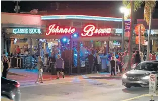  ?? JOHN MCCALL/SOUTH FLORIDA SUN SENTINEL PHOTOS ?? People walk past Johnnie Brown’s on Thursday in downtown Delray Beach. Atlantic Avenue has become a nightlife destinatio­n, but the city is concerned about safety and is considerin­g new rules for bars and restaurant­s.