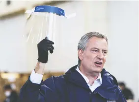  ?? EDUARDO MUNOZ ALVAREZ / GETTY IMAGES ?? New York City Mayor Bill de Blasio holds a face shield at the Brooklyn Navy Yard. The city has recently seen the biggest coronaviru­s outbreak in the United States.