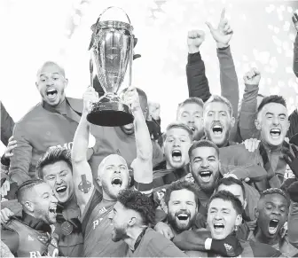  ?? THE CANADIAN PRESS ?? Toronto midfielder Michael Bradley raises the trophy as he and his teammates celebrate their victory over Seattle in MLS Cup Final on Saturday.