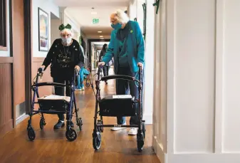  ??  ?? Mann (left) joins fellow resident Helen Caroll, the former thirdgrade teacher to her children, for a little enjoyment during a St. Patrick’s Day scavenger hunt at the assistedli­ving facility.