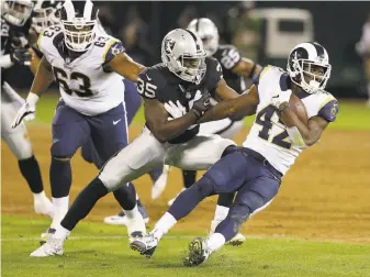  ?? Rich Pedroncell­i / Associated Press ?? Rams running back Justin Davis (42) tries to evade Raiders rookie linebacker Nicholas Morrow during the second half of the second preseason football game at the Coliseum on Aug. 19.