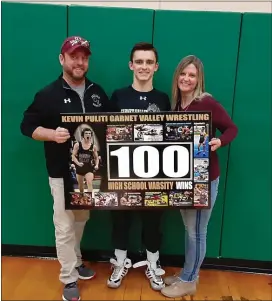  ?? MEDIANEWS GROUP PHOTO ?? Garnet Valley senior wrestler Kevin Puliti holds his king-sized sign with the help of his parents, Mike and Debbi Wednesday night after Puliti registered career win No. 100at Ridley.