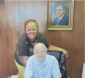  ?? PROVIDED ?? Stephanie Hart with John Stefanos at Cupid Candies. On the wall is a portrait of his father, Polyhronis “Paul” Stefanos.