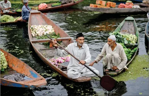  ?? AFP ?? Men gather with their boats laden with vegetables at the floating vegetable market at Dal Lake in Srinagar on Thursday.