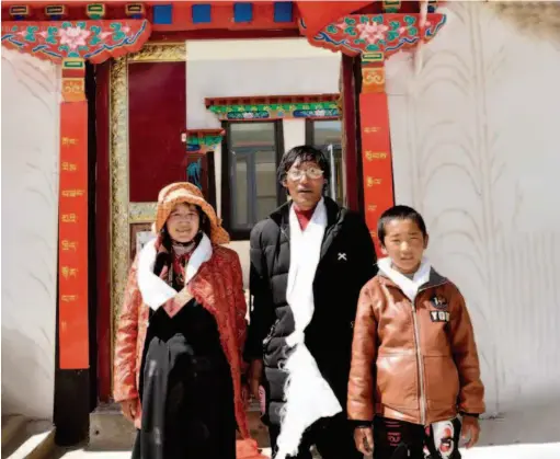  ??  ?? June 18, 2018: Rigzin (center), a former herder in Rungma Township, poses for a photo with his family in front of their new house. by Jogod