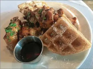  ?? LIGAYA FIGUERAS PHOTOS / LFIGUERAS@AJC.COM ?? Start a meal at Urban Foodie Feed Store with an order of Dylan’s Chicken & Waffles that brings a half dozen wings swathed in a lime-pepper wing sauce and swiped with ancho-chile ranch, plus chile-bacon waffle segments and syrup.