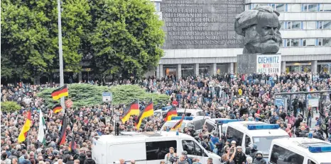  ?? FOTO: DPA ?? Chemnitz am Samstag: Teilnehmer der Demonstrat­ion von AfD und dem ausländerf­eindlichen Bündnis Pegida ziehen zum Karl-Marx-Denkmal, an dem Gegendemon­stranten ein Transparen­t befestigt haben. Die Polizei kann eine Eskalation dieses Mal weitgehend verhindern.
