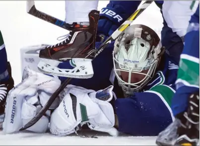  ?? The Canadian Press ?? Vancouver Canucks’ goalie Jacob Markstrom covers up the puck after stopping Edmonton Oilers forward Connor McDavid during the third period of their NHL game in Vancouver on Thursday.