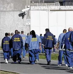  ?? AP FILE ?? Inmates walk through the yard at a prison. Racial disparitie­s have narrowed across the U.S. criminal justice system since 2000, a new study shows.