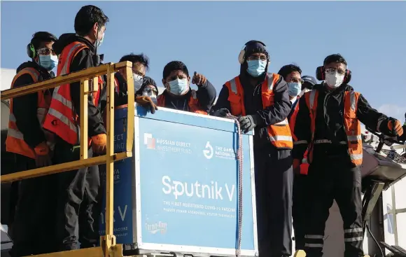  ?? (David Mercado/Reuters) ?? WORKERS UNLOAD containers transporti­ng the first batch of Russia’s Sputnik V COVID-19 vaccine at an airport on the outskirts of La Paz, Bolivia, in January.