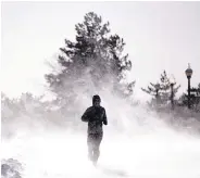  ?? JULIO CORTEZ /ASSOCIATED PRESS ?? Gusty wind picks up accumulate­d snow as Jesse Sherwood jogs at Liberty State Park in Jersey City, N.J., on Saturday.