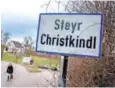  ??  ?? A woman walks by a village sign in Steyr Christkind­le, Austria.