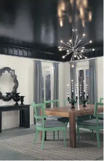  ??  ?? A dark glossy paint gives the ceiling in this dining room a highly reflective, dramatic appearance.