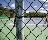  ??  ?? LEFT: The painted cement courts at Whitaker often get scratched from the chain-link fence that surrounds the facility. RIGHT: A zip tie holds the chain-link fence to a pole at the Whitaker tennis facility. The restrooms are a short hike away.