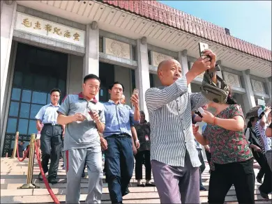  ?? ZOU HONG / CHINA DAILY ?? Visitors take photos after leaving the Chairman Mao Memorial Hall in Tian’anmen Square in Beijing on Friday.