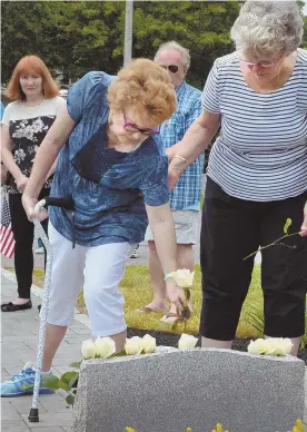  ?? STAFF PHOTO BY CHRIS CHRISTO ?? REMEMBERIN­G: Neil Ellsworth’s sister, Kate, left, and widow, Mary Tocci, put roses on a plaque at Ellsworth McAfee Park last week.