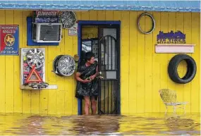  ??  ?? A man peers out a door Tuesday at the river that was — in reality, a severely flooded West Mount Houston Road near Interstate 45 North.