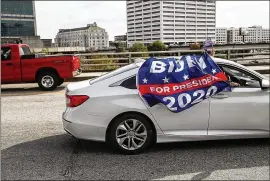 ??  ?? Supporters of Democratic candidate Joe Bidenwave flags as they drive past a group of Trumpsuppo­rters outside State FarmArena, the site of competing demonstrat­ions.