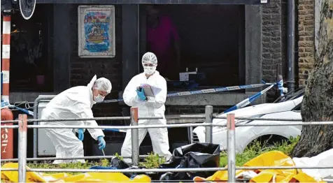  ?? Foto: Geert Vanden Wijngaert, dpa ?? Polizeibea­mte sichern rund um den Tatort auf einer Straße in Lüttich mögliche Beweise für die tödlichen Schüsse.