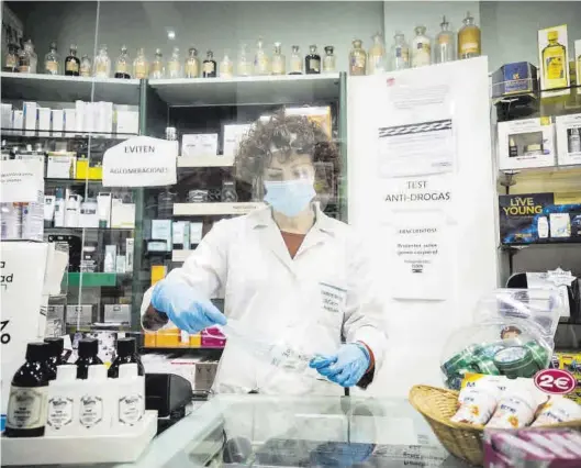  ?? CHUS MARCHADOR ?? Una farmacéuti­ca, totalmente protegida, prepara unas mascarilla­s para su venta, en una botica de Zaragoza.