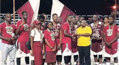  ??  ?? Hazel Cameron, Inter-Secondary Schools Sports Assocation chairperso­n in charge of basketball operations, presents the winning trophy to successful Herbert Morrison High basketball team captain Ralique Grant, while his teammates look on. Herbert...