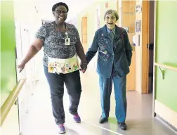  ?? RANDY RISLING TORONTO STAR FILE PHOTO ?? Inga Cherry, right, who died last spring, walks through the hallway with Geva Lindsay, a housekeepe­r at Malton Village in Peel Region in 2017.