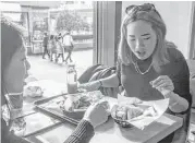  ?? Gilles Sabre / New York Times ?? Liu Xiaoyi, right, editor of a food guide in Shanghai, eats at the first Taco Bell to open in China.