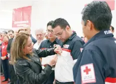  ??  ?? Patricia Acevedo, quien permaneció atrapada 11 horas bajo escombros, colocó el pin conmemorat­ivo al paramédico de la Cruz Roja Diego Arcos, quien la rescató.