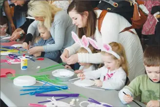  ?? Herald photo Tim Kalinowski ?? Katie Brummund does an Easter craft with her daughters Olivia and Scarlett at the Galt Museum’s “Eggstravag­anza” on Saturday.