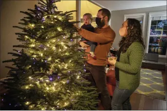  ?? PAULA BRONSTEIN — THE ASSOCIATED PRESS ?? Ani Sirois decorates the family’s Christmas tree with daughter Ida, 2, and husband, Chadwick, at their home in Portland, Ore. The family was tree-shopping nearly a week before Thanksgivi­ng and, for the first time, they were picking their own tree instead of buying a pre-cut one.