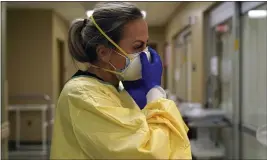  ?? JEFF ROBERSON — THE ASSOCIATED PRESS FILE ?? Registered nurse Chrissie Burkhiser puts on personal protective equipment as she prepares to treat a COVID-19 patient in the emergency room at Scotland County Hospital in Memphis, Mo., on Nov. 24.