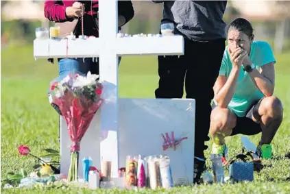  ??  ?? Maria Creed is overcome with emotion as she crouches in front of one of the memorial crosses at Pine Trails Park in Parkland on Friday. The crosses stand in a field at the park to memorializ­e the 17 people killed Wednesday at Marjory Stoneman Douglas...