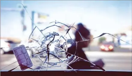  ?? JIM YOUNG/AFP ?? A person walks by a bullet hole in a restaurant window that is linked to the shooting of Manuel Hernandez taken at the 2700 block of West 51st Street in Chicago, Illinois, on September 28.