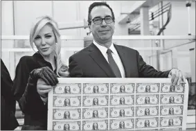  ?? ANDREW HARRER/ BLOOMBERG ?? Treasury Secretary Steven Mnuchin, right, and wife Louise Linton hold an uncut sheet of $1 dollar notes. The new $1 bills, with Mnuchin and U.S. Treasurer Jovita Carranza’s signatures, are expected to go into circulatio­n in December.