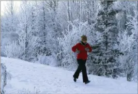  ?? DAN JOLING — THE ASSOCIATED PRESS ?? In this Tuesday photo, a runner jogs on a trail at Westcheste­r Lagoon in Anchorage, Alaska. With ice present on city streets for up to seven months per year, most walkers and runners use footwear that has built-in studs or attached cleats as a safety...