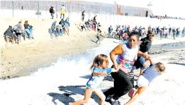  ?? — Reuters photo ?? File photo shows Meza (centre) from Honduras, part of a caravan of thousands from Central America running away from tear gas with her five-year-old twin daughters in front of the US-Mexico border wall in Tijuana.