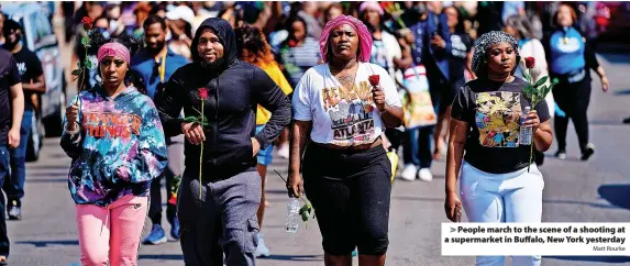  ?? Matt Rourke ?? People march to the scene of a shooting at a supermarke­t in Buffalo, New York yesterday