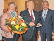 ?? FOTO: CLAUDIA STECKELR ?? Der Justizmini­ster Guido Wolf (rechts) zeichnet Herbert Tiny am Montagaben­d mit der Staufermed­aille aus. Seine Frau Irmgard Tiny bekommt Blumen.