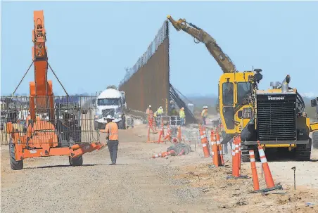  ?? Randy Hoeft / Yuma Sun ?? Constructi­on workers install a new section of a 30foothigh barrier at a site south of Yuma, Ariz., at the border with Mexico.