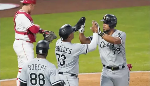  ?? ASHLEY LANDIS/AP ?? Jose Abreu high-fives Yermin Mercedes after hitting a grand slam in the third inning Friday night against the Angels in Anaheim, Calif.