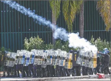  ?? (AP/Eraldo Peres) ?? Riot police fire tear gas Tuesday at Indigenous protesters outside Congress in Brasilia.