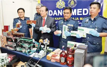  ??  ?? Janathan (centre) and other Customs officers showing the contraband and cash seized from the house.