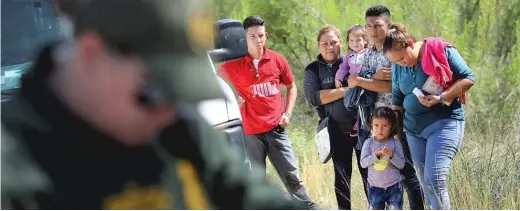  ?? JOHN MOORE/ GETTY IMAGES ?? Central American asylum seekers wait as U. S. Border Patrol agents take groups of them into custody Tuesday in Texas. The families were then sent to a U. S. Customs and Border Protection processing center for possible separation.