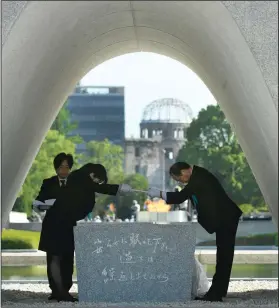  ?? Yohei Nishimura/Kyodo News via AP ?? Mourning: Hiroshima Mayor Kazumi Matsui, right, dedicates the list of the victims of atomic bombing to the cenotaph during a ceremony to mark the 73rd anniversar­y of the bombing at Hiroshima Peace Memorial Park in Hiroshima, western Japan, Monday....