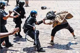  ?? YESHIEL PANCHIA/AP ?? A police officer and a student protester clash Monday at the University of the Witwatersr­and in Johannesbu­rg amid a bitter national dispute over education funding.