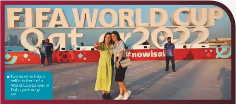  ?? AFP ?? ■ Two women take a selfie in front of a World Cup banner in Doha yesterday.